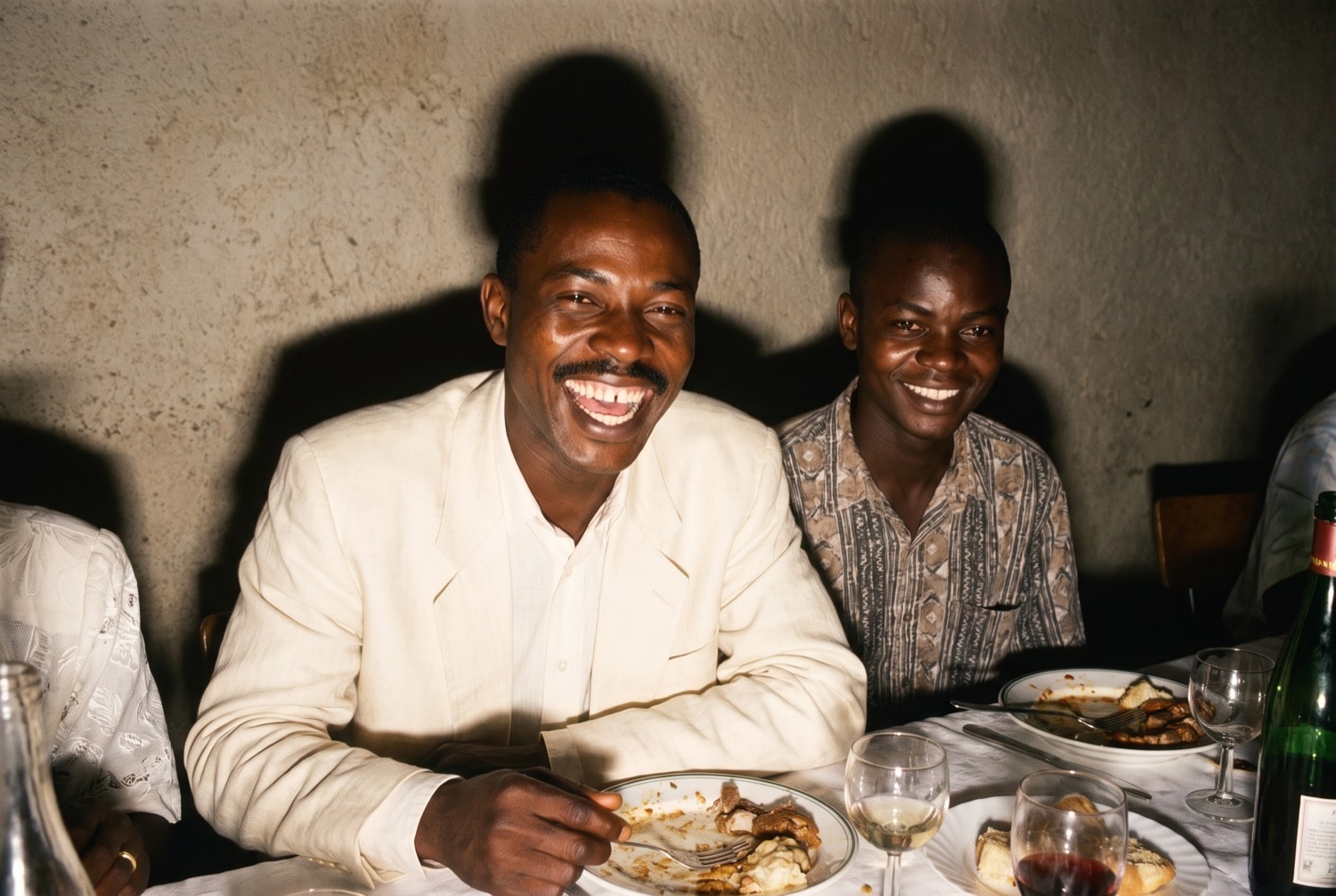 Two brothers laughing at a wedding table, lit by hard direct flash.